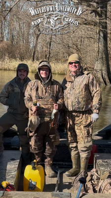 Three people in camouflage hunting gear stand on a boat, holding ducks, with trees and water in the background; "Waterfowl Unlimited Guide Service" logo is visible at the top.